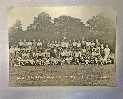 Four rows of eighty boys and staff, the front cross-legged on the ground, the second seated and the third and fourth standing