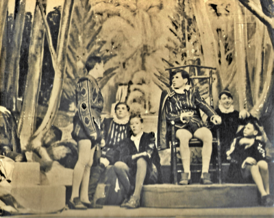 One standing actor addressing a seated actor with two actors sat on the floor on each side of him