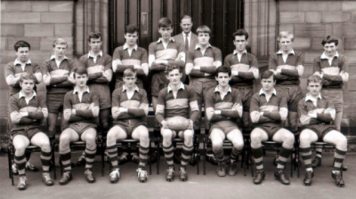 Formal photograph showing nine players standing behind seven seated players with Mr Birchall standing at the very back