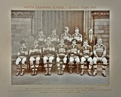 Formal photograph showing four team members standing on the front steps with Mr Birchall to their right behind seven seated team members