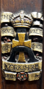 Cross within an A surmounted by a crown and surrounded by a scroll giving the regimental name