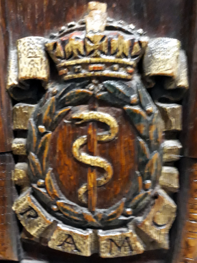 Aesculapian snake surrounded by laurel wreath surmounted by a crown with RAMC underneath