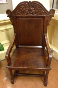 One of three carved chairs with arms