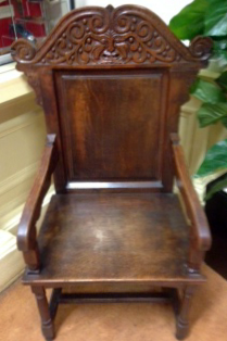 One of three carved chairs with arms