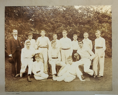 Formal photograph showing seven players standing in front of three seated players with two players seated on the grass and Sergeant Wheatley on the left of the standing players