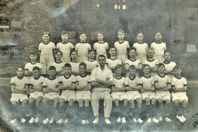 Formal photograph showing seven gymnasts standing behind eight gymnasts standing behind ten seated gymnasts with Mr 