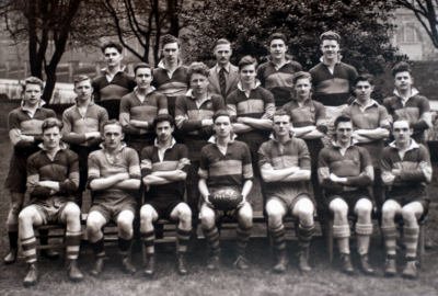 Formal photograph showing nineteen players of the 1949/50 Rugby Team in three rows of seven, eight and four from front to back with Mr Burchall in the middle of the back row