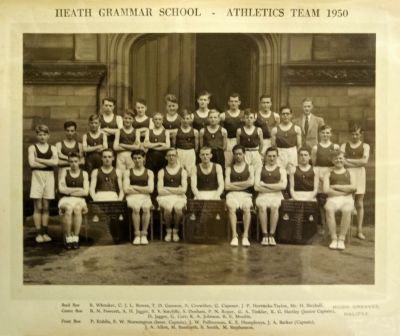 Formal photograph showing three rows of athletes, two rows standing with Mr Birchall to the right of the back row and one row seated with three trophies in front of them
