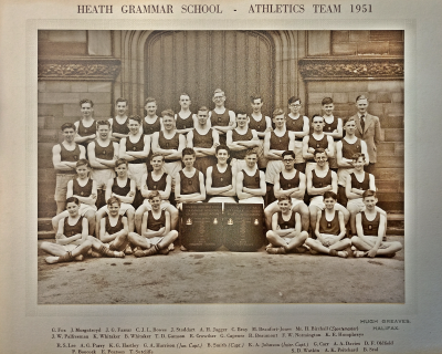 Formal photograph showing nine people standing behind another nine standing behind nine seated with six sitting crosslegged in front of them with two trophies in the middle of them