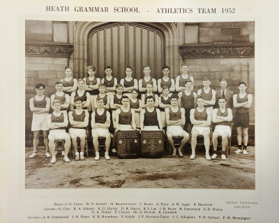 Formal photograph showing seven people standing behind twelve standing behind eight seated with two trophies in front of them