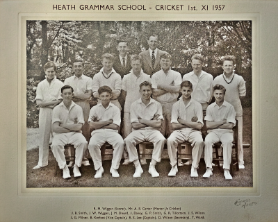 Formal photograph showing the Scorer and Master i/c Cricket standing behind seven standing players behind five seated players