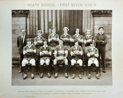 Formal photograph showing five team members standing on the front steps with Mr Birchall to the left of the row and an unknown person to the right behind five seated team members