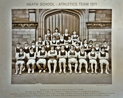 Formal photograph showing four team members standing on the front steps of the school behind six standing team members who are behind twelve standing team members behind nine seated team members