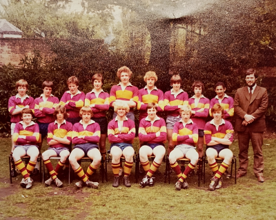 Nine boys standing with Mr Kay on their right behind seven seated boys