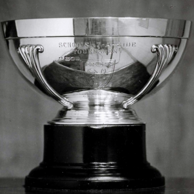 Photograph showing a bowl-shaped trophy inscribed ‘Schools 7 a side tournement’ on a stand
